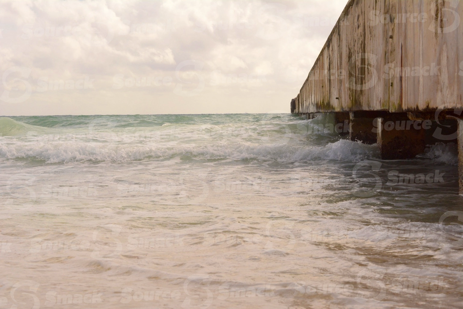 Ocean waves crashing on a beach with a dock  in Mexico