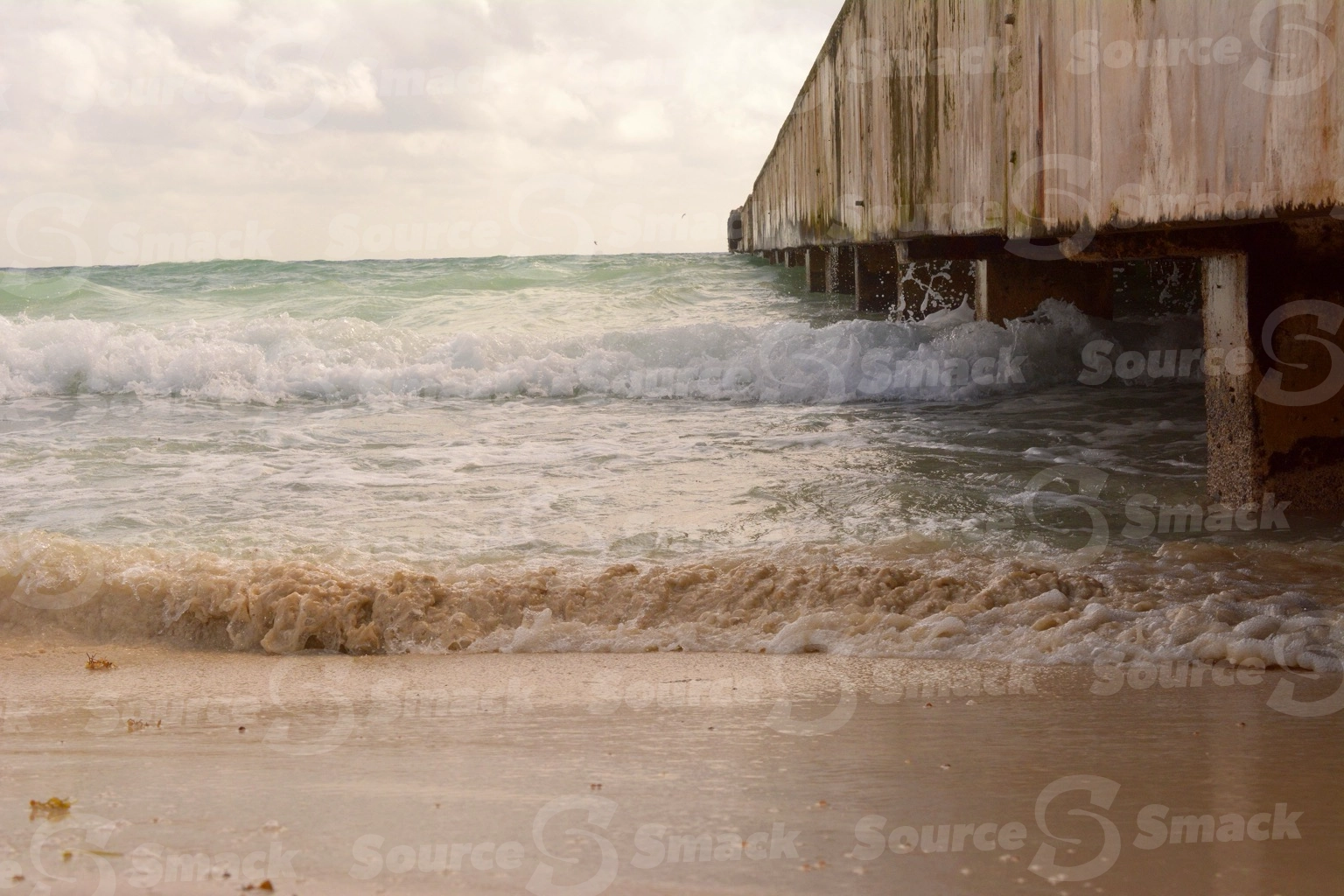 Ocean waves crashing on a beach with a dock  in Mexico